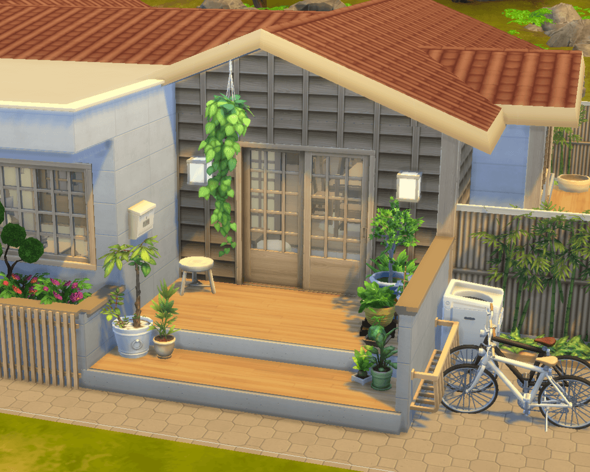Thumbnail view of the exterior front door of house. lots of plants in planters and in flower beds, bikes off the side.
