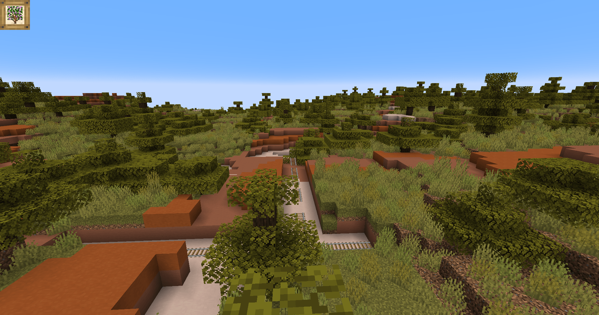 An abandoned mineshaft threads through the terracotta and coarse dirt surface of a Wooded Badlands, exposing old rail tracks to the stunted trees that have reclaimed it.