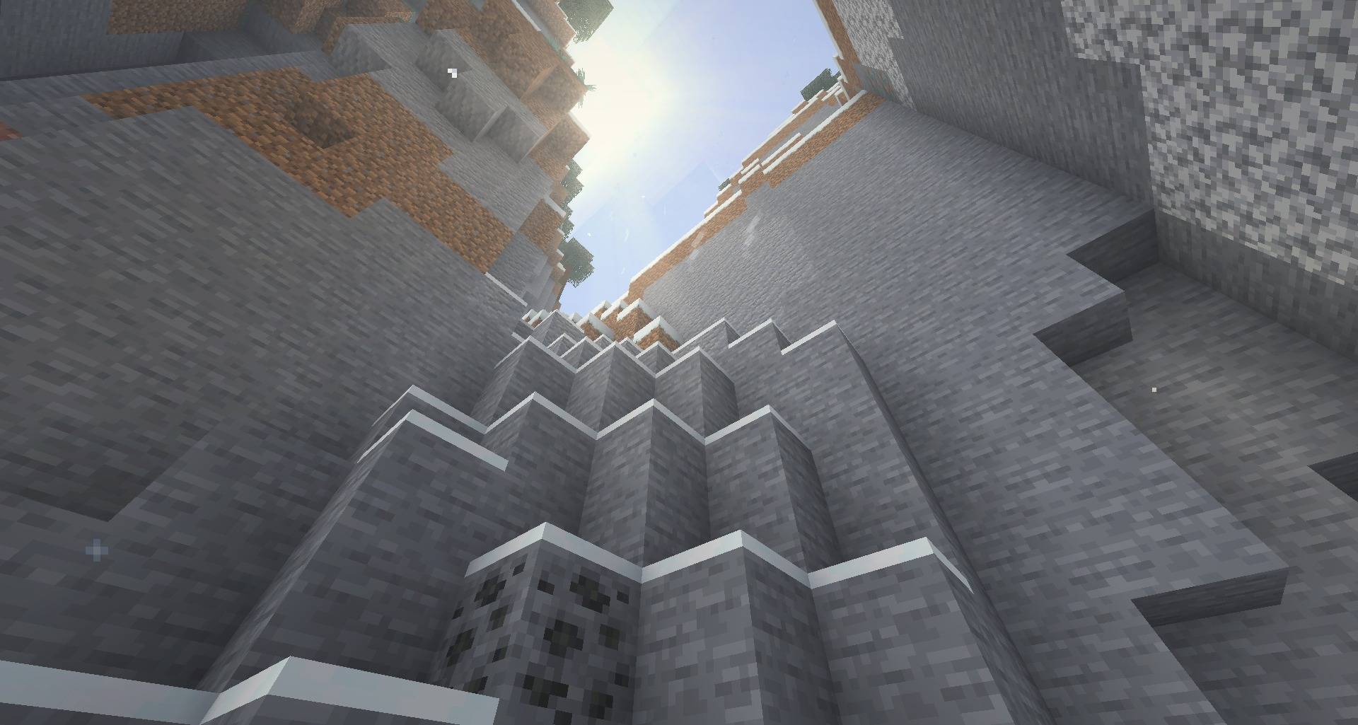 Looking up snowy cliffs towards the sun