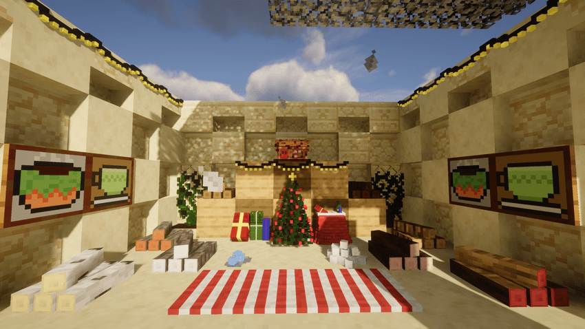 A Minecraft christmas scene inside an open sandy room with a blue sky above. It features a decorated Christmas tree with wrapped gifts, a red-and-white striped rug on the floor, large paintings of green mugs on the walls, and stacks of wooden blocks lining the area.